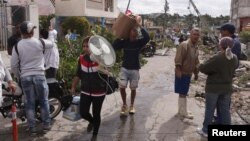 Cubanos cargan las pertenencias que han podido sacar de entre los escombros que dejó el tornado que arrasó varios barrios de La Habana