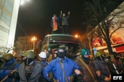 Cientos de protestantes custodían un autobús con policías retenidos, a quienes después dejaron ir a casa este 21 de febrero de 2014 durante protestas en el centro de Kiev (EFE)
