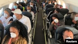Personas en un vuelo de Caracas a La Habana se protegen con máscaras por temor al contagio con el coronavirus. REUTERS/Carlos Jasso