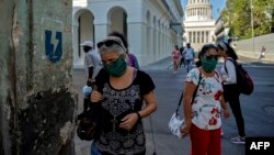 Mujeres usando máscaras caminan por una calle de La Habana