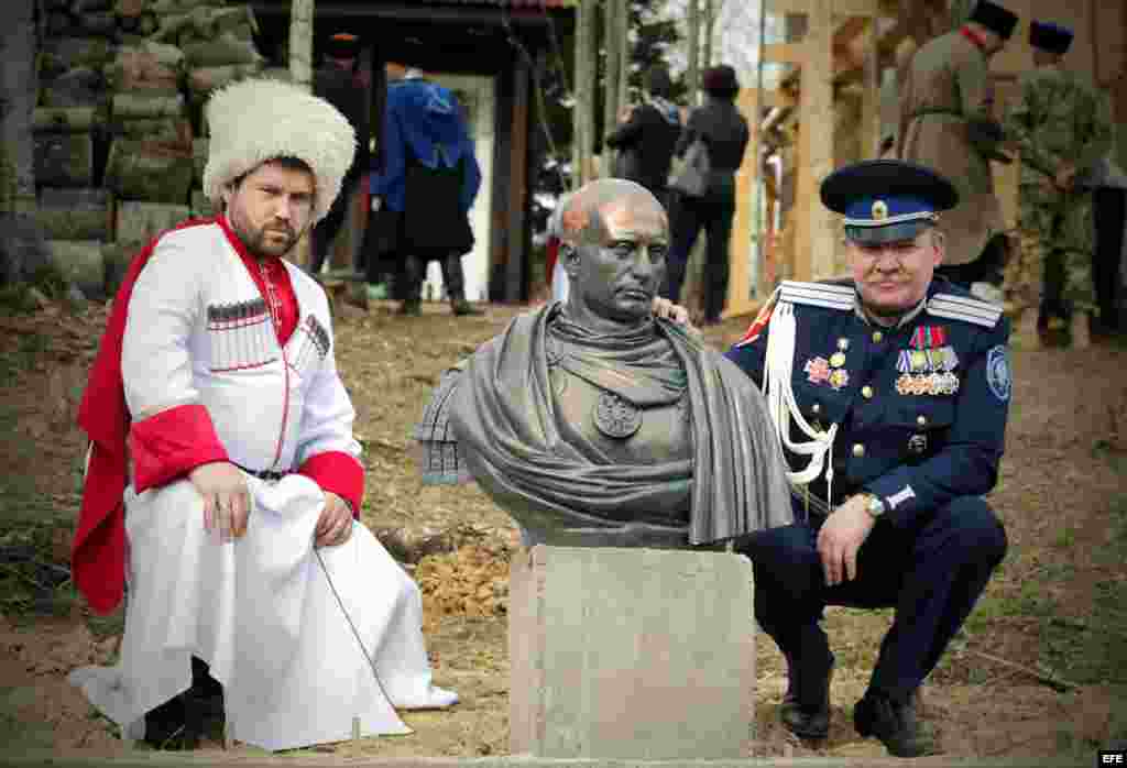Dos cosacos posan junto al busto de Putin.