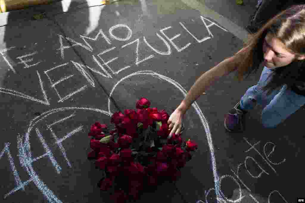 Una estudiante coloca un ramo de rosas al finalizar la marcha convocada por los universitarios opositores en Caracas hoy, viernes 14 de febrero de 2014.