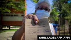 Una mujer muestra su tarjeta de vacunación tras recibir la primera dosis de Abdala contra el COVID-19. (YAMIL LAGE / AFP)