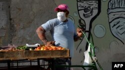 Un vendedor de vegetales en una calle de La Habana usa una máscara para protegerse del coronavirus. (YAMIL LAGE / AFP)
