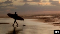 Jóvenes practican surf en una playa (Archivo)