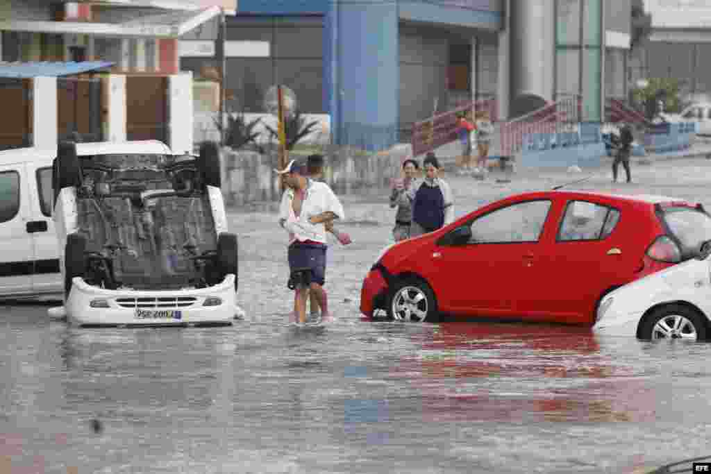  Varias personas observan vehículos averiados por las inundaciones hoy, martes 24 de enero de 2017, en La Habana (Cuba).