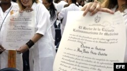 Varios jóvenes médicos muestran sus diplomas de recién graduados.