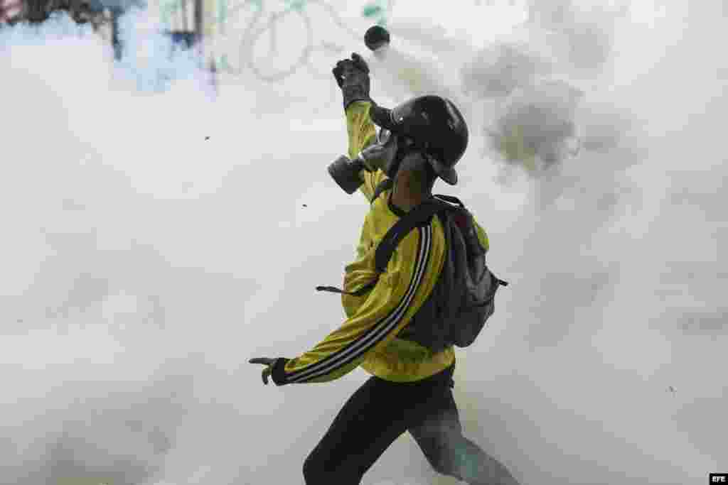 Un manifestante se cubre el rostro con una máscara antigás al enfrentarse con agentes de la Policía Nacional Bolivariana (PNB) en Caracas (Venezuela).