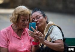 Aída Puppo (i), de 71 años, habla en video conferencia con su hijo que vive desde hace 20 años en Estados Unidos, al aprovechar una señal de internet en una plaza de Centro Habana en marzo de 2016, en La Habana.