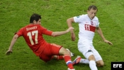 El jugador polaco Rafal Murawski disputa el balón con Alan Dzagoev (i) de Rusia hoy, martes 12 de junio de 2012, durante el juego del Grupo A de la Eurocopa 2012, que se disputa en Varsovia (Polonia).