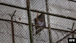 El dirigente político de oposición Leopoldo Lopez se asoma por una ventana de su celda en la Prisión Militar de Ramo Verde, desde donde saluda a su esposa, Lilian Tintori y su madre, Antonieta Mendoza de López, el sábado 15 de noviembre del 2014, en la ciudad de los Teques, Venezuela. 