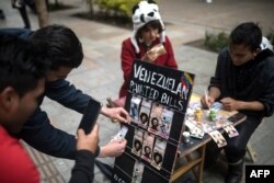 Una pareja de migrantes venezolanos pinta billetes en las calles de Bogotá para protestar contra la situación económica de su país. (Archivo)