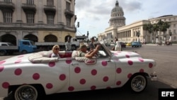  Turistas se pasean en un auto clásico cerca del Capitolio, en La Habana.