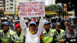 Una mujer sostiene un cartel donde critica a Maduro por enviar petróleo a Cuba