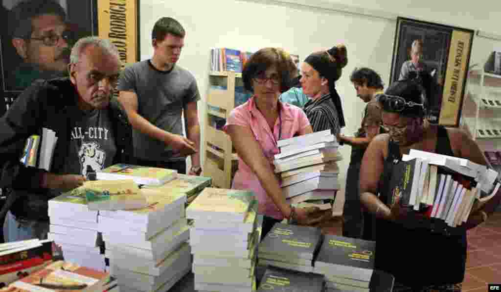 Varios asistentes a la Feria del Libro en busca de algunos de los más de 2.000 títulos a la venta, trabajadores en el evento.