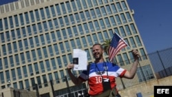 Un hombre posa con sus documentos migratorios frente a la Embajada de EEUU.