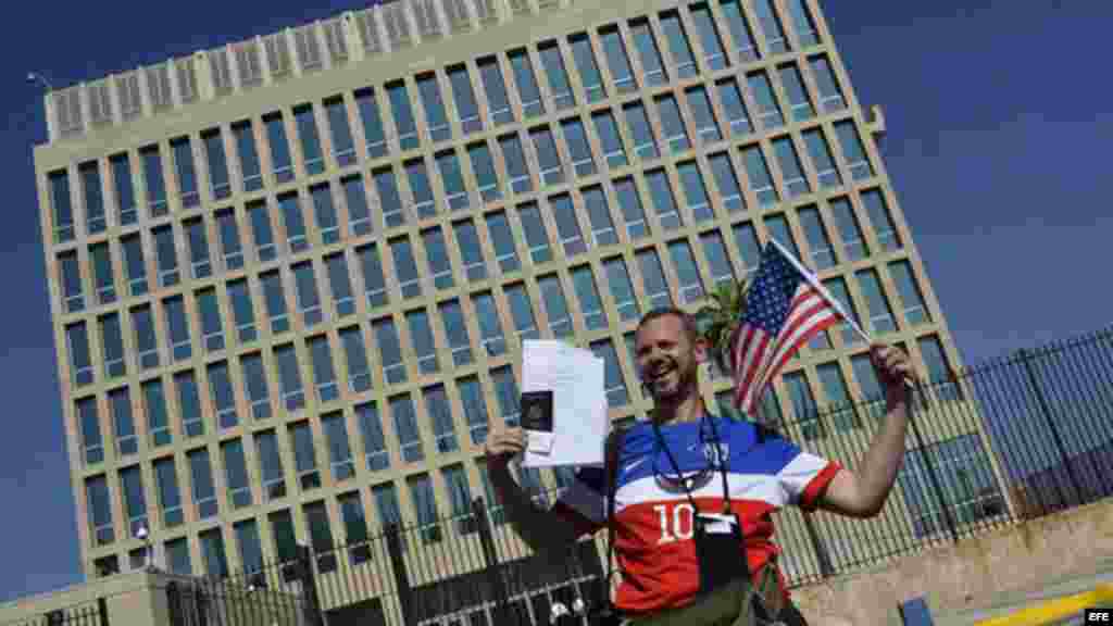 Un hombre posa con sus documentos migratorios frente a la Embajada de los EEUU