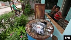 Varias personas permanecen junto a botellas de ron vacías en una vivienda del barrio Alturas de la Lisa en La Habana donde hace pocos días se produjo un caso de intoxicación con alcohol metílico o "de madera" comercializado ilegalmente.