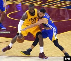 El jugador de Warriors Stephen Curry (d) marca a LeBron James (i), de Cavaliers, durante el cuarto partido de la Serie Final de la NBA entre Warriors y Cavaliers.