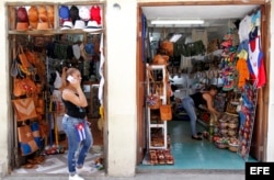 Una mujer habla por teléfono frente a dos negocios privados de venta de artesanías en La Habana (Cuba).