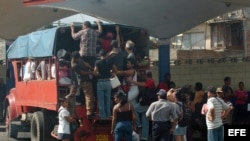 Varias personas intentan subir a un camión particular que funciona como transporte público en Santiago de Cuba. EFE