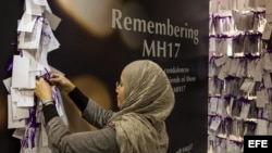 Una mujer cuelga un mensaje en homenaje a los pasajeros y la tripulación del vuelo MH17 de Malaysia Airlines en un centro comercial en Kuala Lumpur (Malasia)