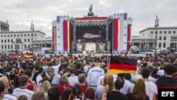 Simpatizantes de la selección nacional alemana de fútbol siguen por televisión la salida de los jugadores de Brasil en la llamada "Milla del aficionado" en la Puerta de Brandeburgo en Berlín (Alemania).