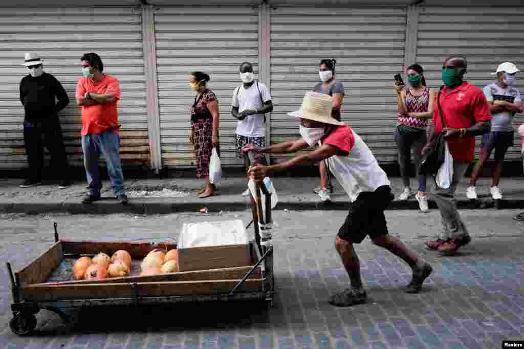Un vendedor ambulante empuja un carrito con verduras mientras la gente espera para comprar comida en medio de la preocupación por la propagación del COVID-19 en La Habana. (REUTERS/Alexandre Meneghini)