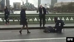 Captura de vídeo que muestra a varias personas mientras atienden a un herido tras un tiroteo en el Wetminster Bridge junto al Parlamento en Londres, Reino Unido, hoy, 22 de marzo de 2017. 