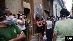 Cubanos se protegen con máscaras durante la espera para comprar en una tienda en La Habana.