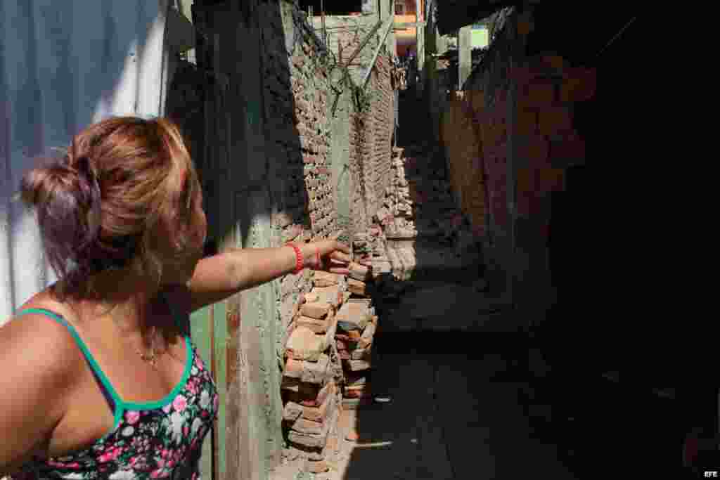 Una mujer señala un muro a punto de caer de un callejón desplomado hoy, lunes 18 de abril de 2016, tras un fuerte sismo de 7,8 grados que sacudió al país en la zona hotelera de Tarqui en Manta (Ecuador).