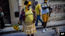 Una mujer con girasoles y una máscar para protegerse del coronavirus en una calle de La Habana. (AP/Ramon Espinosa)