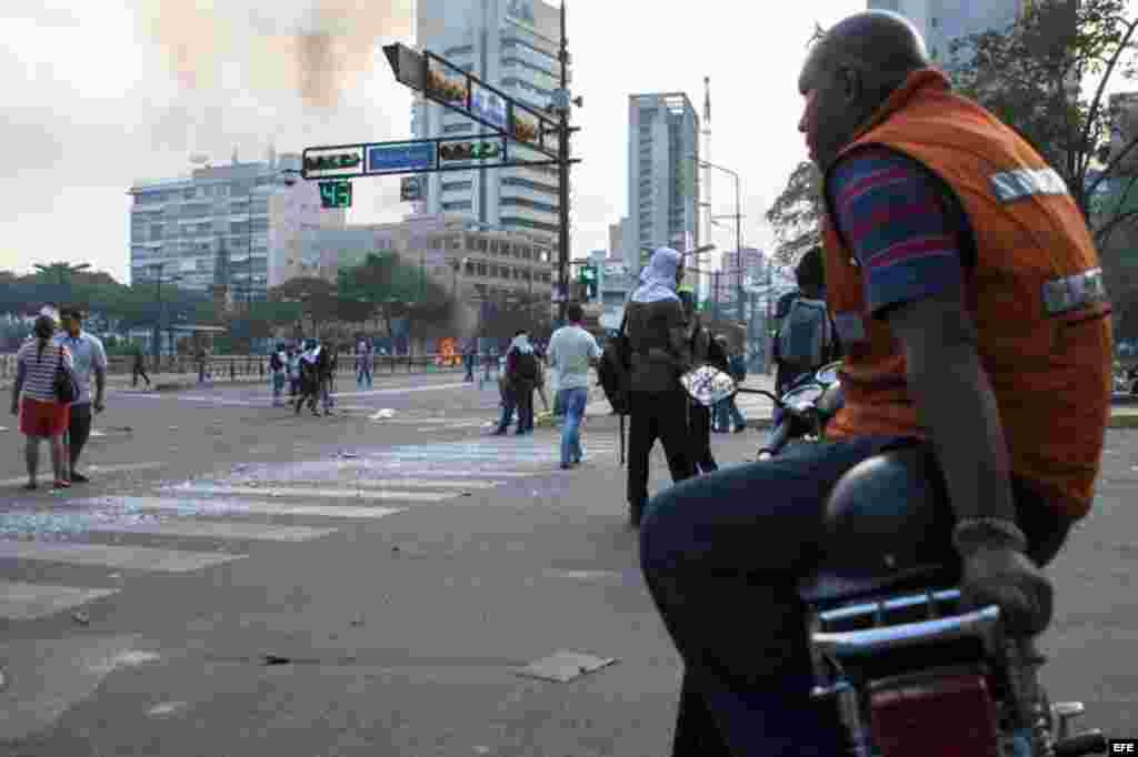 Un trabajador mototaxista observa los disturbios en la Plaza Altamira
