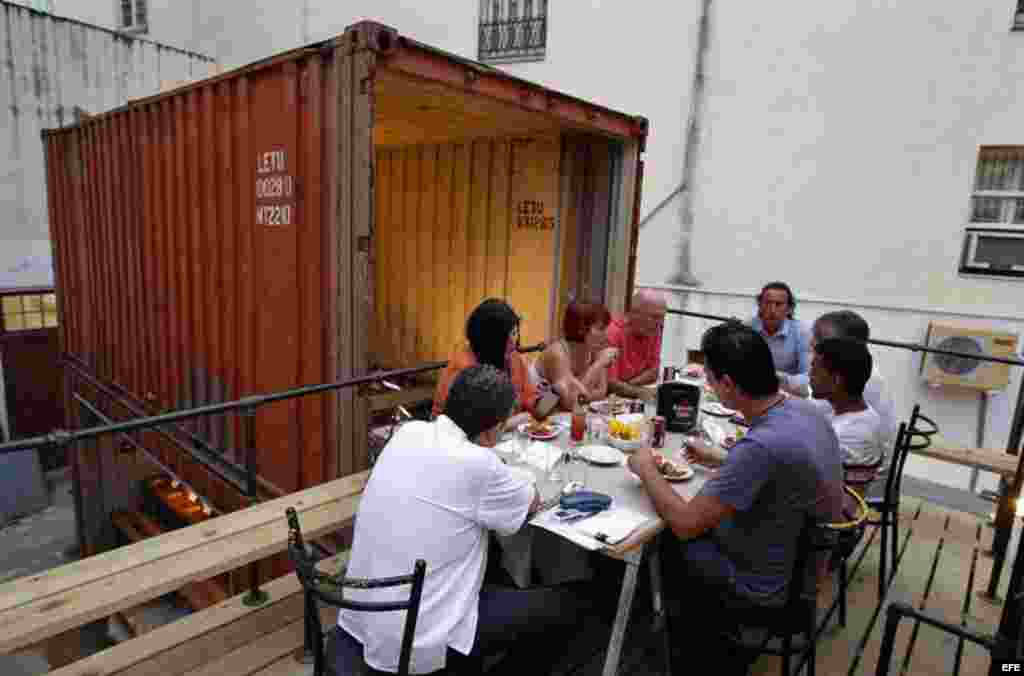 Proyecto Paladar Bienal Habana. Varias personas comen junto a un contenedor que hace parte del montaje de la cocina en donde preparan alimentos los chefs que participan en el Proyecto.