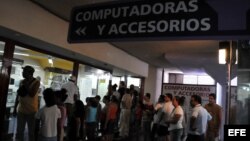 Varias personas hacen cola para comprar computadoras, o simplemente curiosear en una tienda de La Habana.