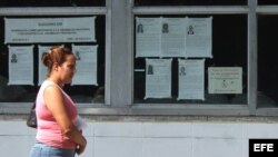Una mujer camina junto a carteles alusivos a las elecciones de los delegados a las asambleas nacionales y provinciales del Poder Popular en Cuba. 