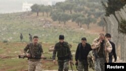 Combatientes portan sus armas mientras avanzan hacia sus posiciones cerca de la línea de frente contra las fuerzas leales al presidente sirio Bashar al-Assad en la aldea de Ratian, al norte de Alepo el 17 de febrero de 2015.