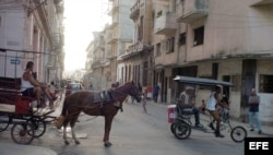 Un carretón con un caballo y un bicitaxi circulan por una calle de La Habana, Cuba.
