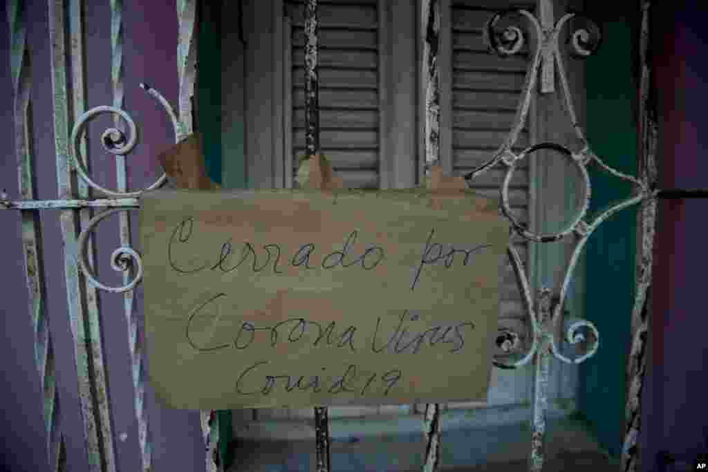 Un cartel de &quot;Cerrado por coronavirus COVID-19&quot; cuelga de la puerta de un negocio en La Habana. (AP/Ismael Francisco)