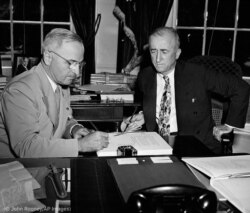 El presidente Harry Truman (izda.) firma la carta de la ONU para completar su ratificación, mientras el secretario de Estado James Byrnes observa. (© John Rooney/AP Images)