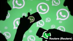 Hombres posan con teléfonos inteligentes frente al logotipo de Whatsapp que se muestra en esta ilustración el 14 de septiembre de 2017. REUTERS / Dado Ruvic.