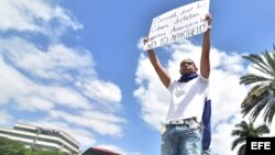 Cubano sostiene un cartel este martes en una manifestación frente a las oficinas de cruceros Carnival en Miami.