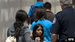 Mahalia Velazco (c), de 8 años, observa a un oficial estadounidense de fronteras, mientras ingresa a Estados Unidos con su familia por la garita de San Ysidro en la frontera entre EEUU y Tijuana, México.