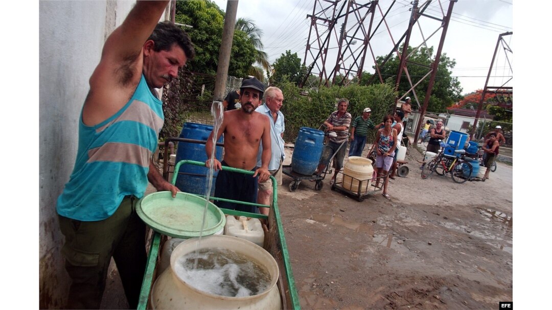 Varias personas con cubos y tanques hacen cola en un "Punto de agua" del barrio Alcides Pino, Holguín
