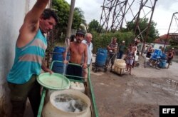 Varias personas con cubos y tanques hacen cola en un "Punto de agua" del barrio Alcides Pino, Holguín