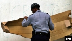 Fotografía de archivo de un policía cubano tapando mensajes antigubernamentales. EFE/Enrique de la Osa