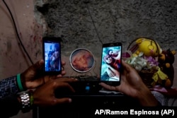 Familiares muestran fotos de los hermanos Román, detenidos y acusados de participar en protestas del 11 de julio, 2021.
