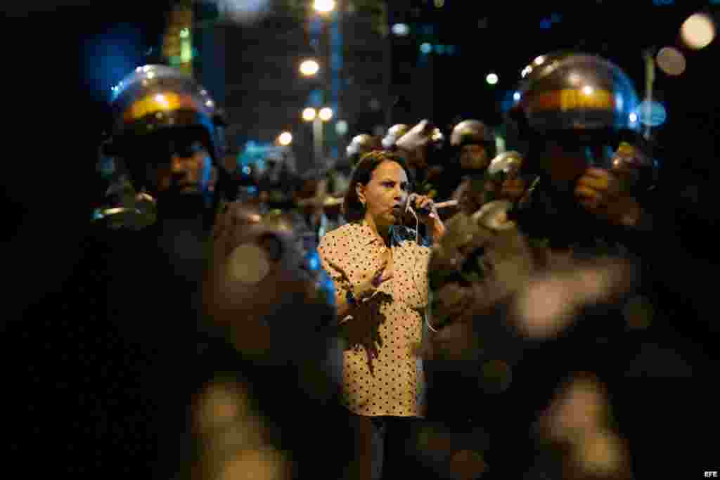 La esposa del alcalde mayor de Caracas Antonio Ledezma, Mitzy Capriles, habla por teléfono en medio de miembros de la Policía Nacional Bolivariana (PNB) que custodian el edificio del Servicio Bolivariano de Inteligencia Nacional (SEBIN) (19 de febrero, 2015).