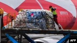 Un trabahjador descarga paquetes de ayuda humanitaria para venezolanos en el Aeropuerto Internacional Hato, en Willemstad, Curazao. 