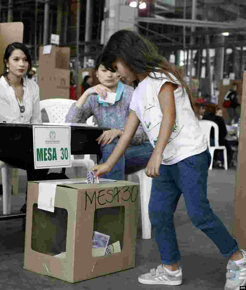 Una niña deposita el voto de su mamá por el plebiscito sobre el acuerdo de paz hoy, domingo 2 de octubre de 2016, en Medellín.